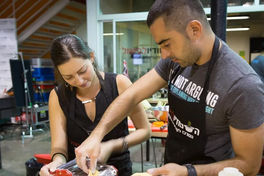 A couple preparing a dish together at a shared station